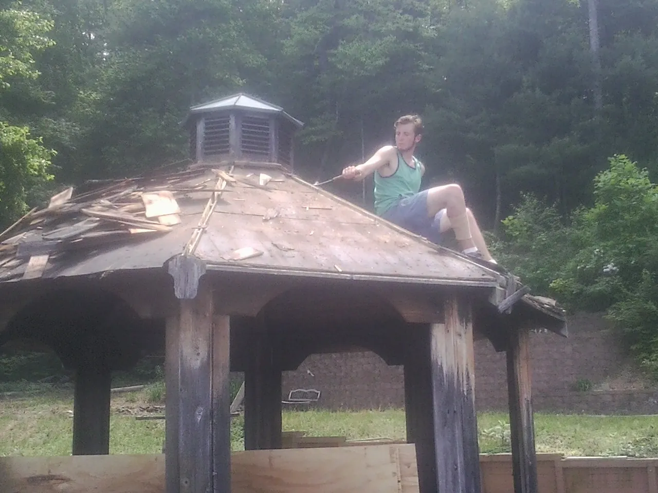 Tearing the old roof off a wooden gazebo before new shakes in Henryville