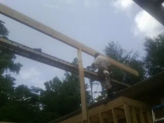 Carpenter setting a ridge beam over a new addition frame — Ice Dam Removal by Roofing Brothers in Henryville