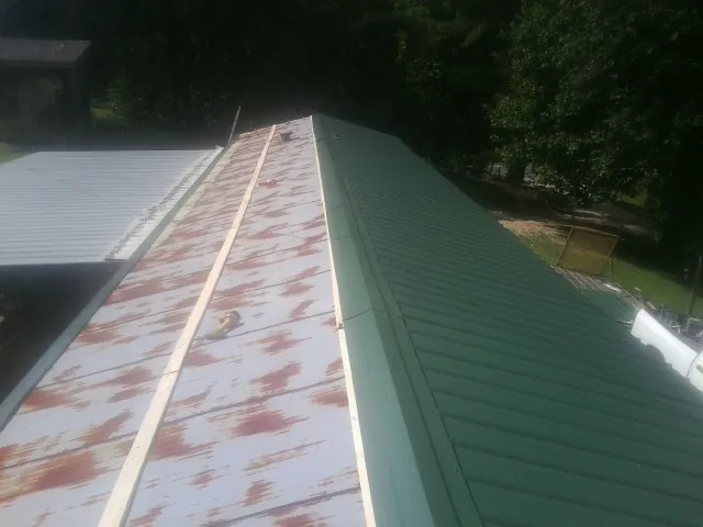 Old rusted panels beside newly installed green metal roofing — Wind Damage Roof Repair by Roofing Brothers in Henryville
