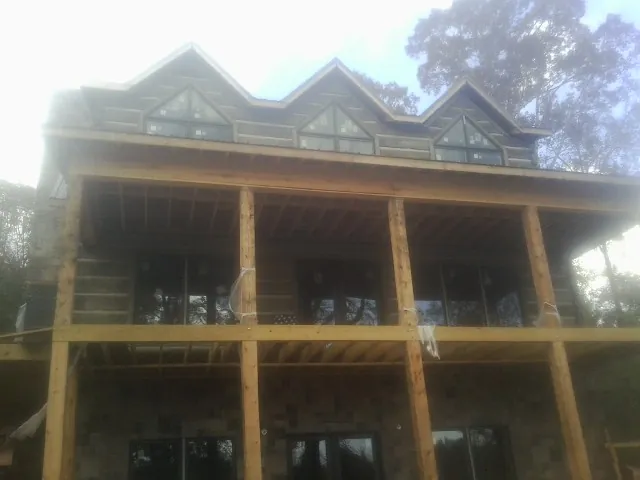 Dormers and porch framing on a large log home under construction — Roof Coating work by our crew in Henryville
