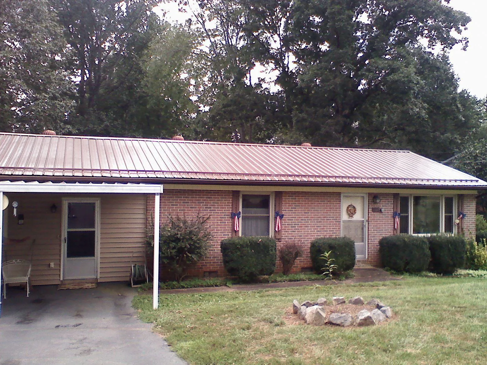Bronze metal roof and carport on a brick ranch home — Roof Repair work by our crew in Henryville