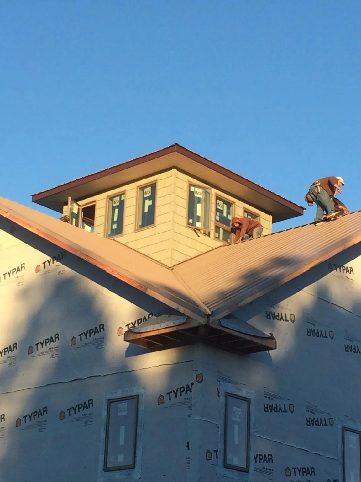 Roofers working around a rooftop cupola on a new metal roof at sunset — Roof Waterproofing in Henryville by Roofing Brothers